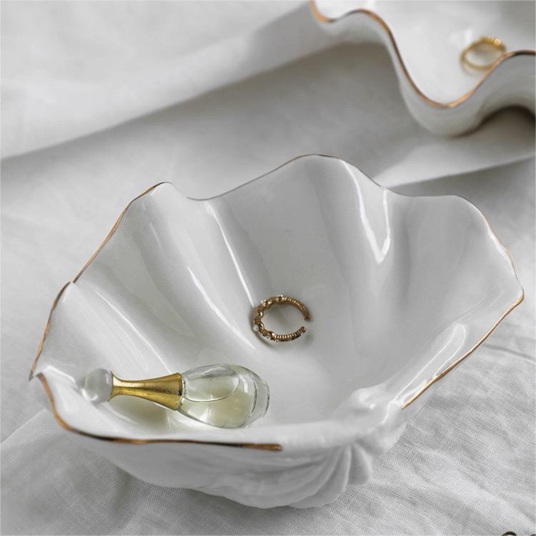 White ceramic shell craft product bowl with gold rim, elegant decorative dish for jewelry, snacks, or home decor.