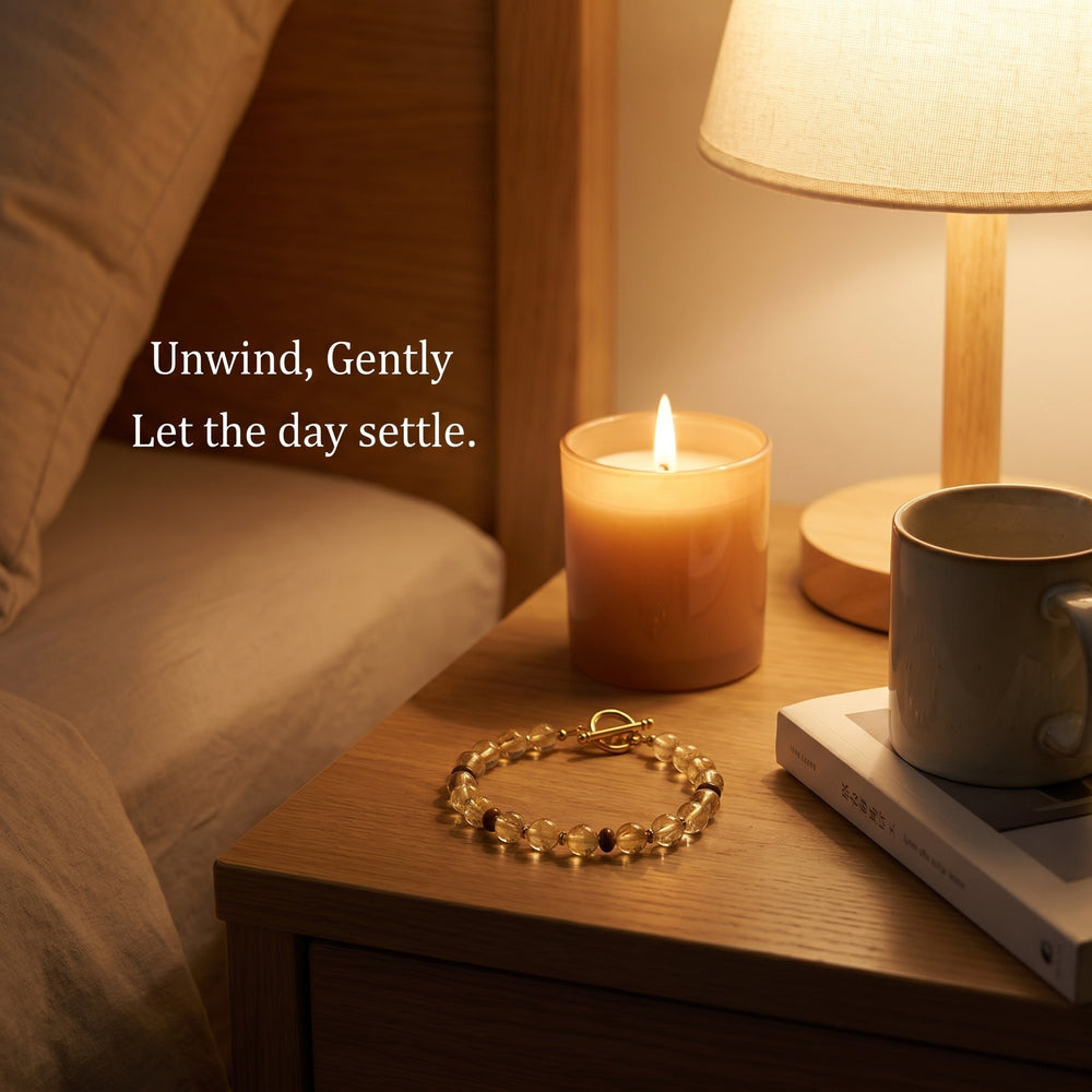 Golden crystal bracelet resting on a wooden table beside a steaming coffee mug and an open book, representing a gentle start to the day and mindful calm.