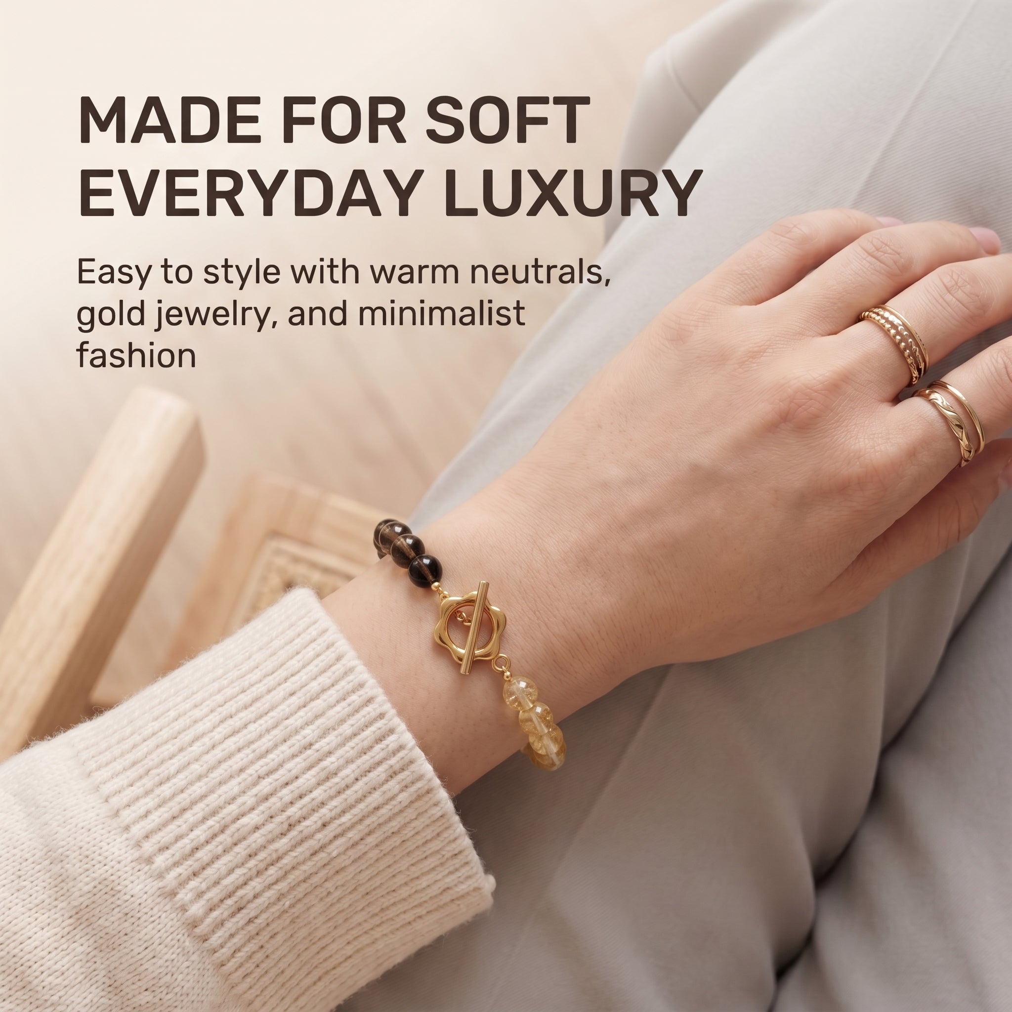Woman styling golden crystal bracelet with soft neutral fashion outfit